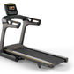 Matrix TF50 folding treadmill with gray frame, black running deck, gold accents, and digital display console on white backgro