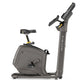Gray Matrix upright exercise bike with black seat, digital console, and extended handlebars on white background