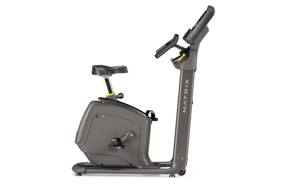 Gray Matrix upright exercise bike with black seat, digital console, and extended handlebars on white background