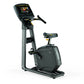 Black and gray upright exercise bike with digital display screen, handlebar, seat, and foot pedals on white background