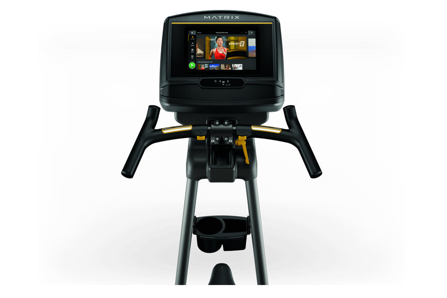 Matrix U50 upright exercise bike with black frame, gold accents, touchscreen console displaying workout content, and dual han