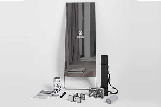 Lululemon Studio Mirror Pro with reflective surface, displayed with accessories including black carrying case, gray yoga mat,