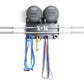 Black wall-mounted weight storage rack with two gray dumbbells, steel barbell bars, and colorful resistance bands hanging fro