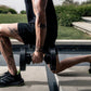 Person performing dumbbell exercise with black adjustable weights in outdoor fitness setting