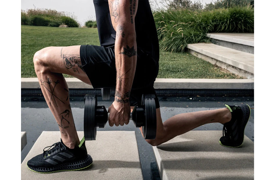 Person performing dumbbell exercise with black adjustable weights in outdoor fitness setting