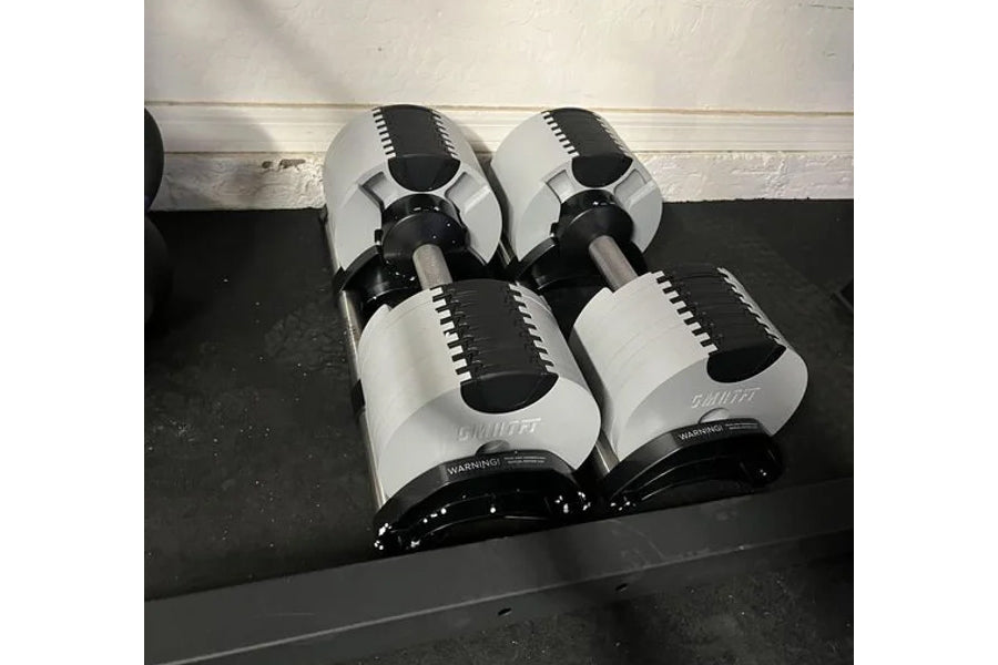 Pair of white and black adjustable dumbbells with metal handles on black weight stand