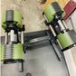 Pair of neon green adjustable dumbbells with black metal handles on black NÜOBELL stand, flat lay on concrete floor