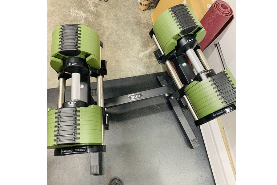 Pair of neon green adjustable dumbbells with black metal handles on black NÜOBELL stand, flat lay on concrete floor