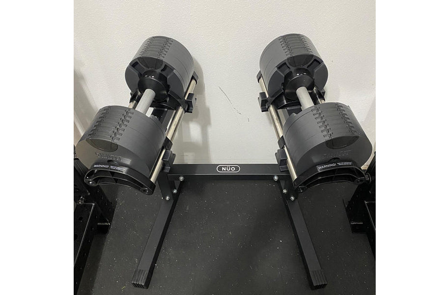 Pair of gray and black adjustable dumbbells on black NUO double-legged stand, flat lay view