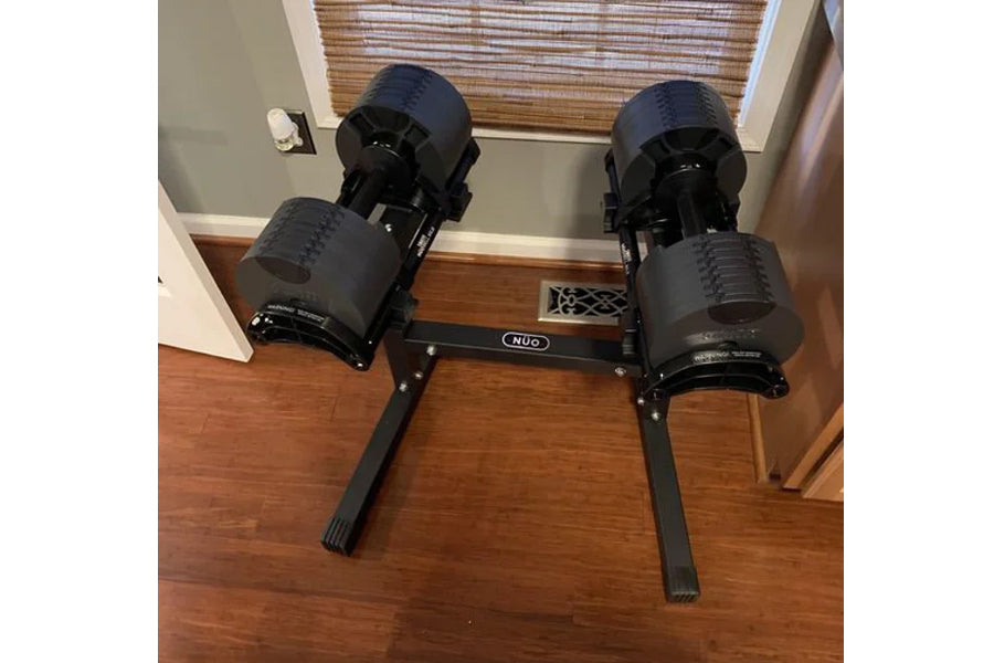 Nüobell adjustable dumbbell stand with two black dumbbells on wooden floor, front view