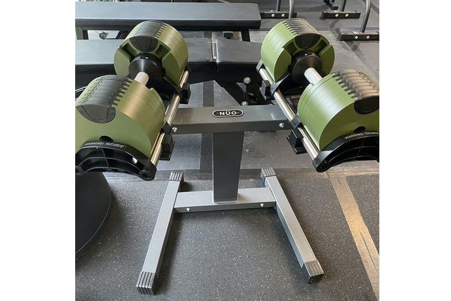 NÜOBELL adjustable dumbbell stand with neon yellow and black weights on gray floor, single-leg steel frame design