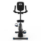 Black upright exercise bike with digital display, padded seat, dual handlebars, and blue accents on pedals and base, front vi