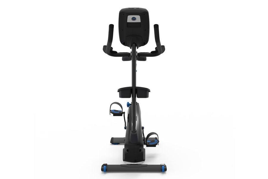 Black upright exercise bike with digital display, padded seat, dual handlebars, and blue accents on pedals and base, front vi