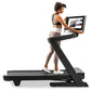 Woman in black and white athletic wear running on black NordicTrack treadmill with tablet display mounted on console