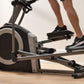 Person wearing black sneakers on NordicTrack commercial elliptical with black and gray frame on wooden floor
