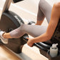 Person in white workout leggings using black NordicTrack recumbent exercise bike with hand grips and display console
