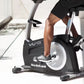 NordicTrack Commercial VU 19 upright exercise bike in black and white, worn by model in black workout clothes