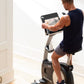 Man in navy sleeveless shirt using NordicTrack VU 29 upright exercise bike with digital display screen in home gym setting