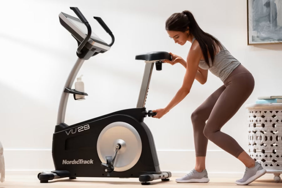 Woman using black and silver NordicTrack VU 29 upright exercise bike in home gym setting