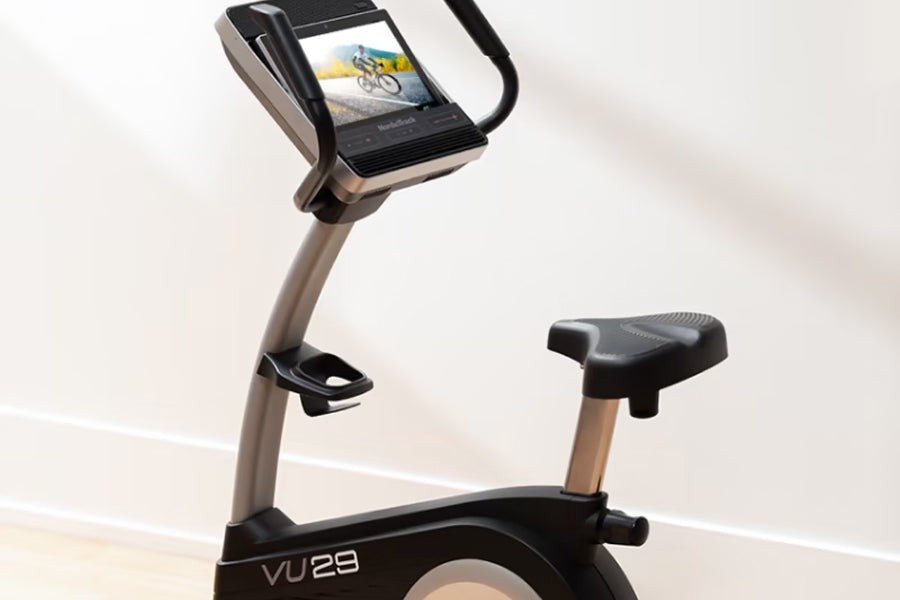 NordicTrack Commercial VU 29 upright exercise bike with black frame, tan handlebar, digital display showing cyclist, and blac