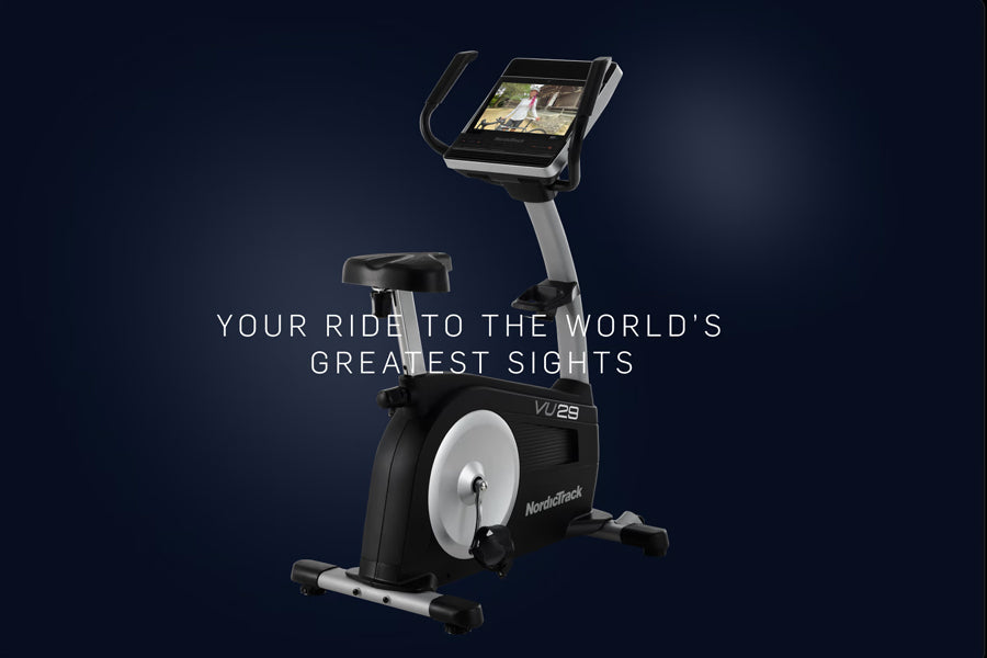 NordicTrack Commercial VU 29 upright exercise bike with digital display screen, white wheel, and black frame on dark blue bac