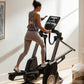 Woman wearing gray sports bra and leggings using black NordicTrack elliptical machine with digital display in bright home gym