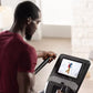 Man in burgundy t-shirt using NordicTrack FS10i elliptical with touchscreen display in home setting