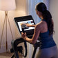 Woman using black NordicTrack elliptical with touchscreen display in home gym setting