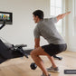 Man using black NordicTrack rowing machine with digital touchscreen display in bright room with windows