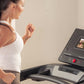 Woman in white tank top running on NordicTrack EXP 7i treadmill with black console display