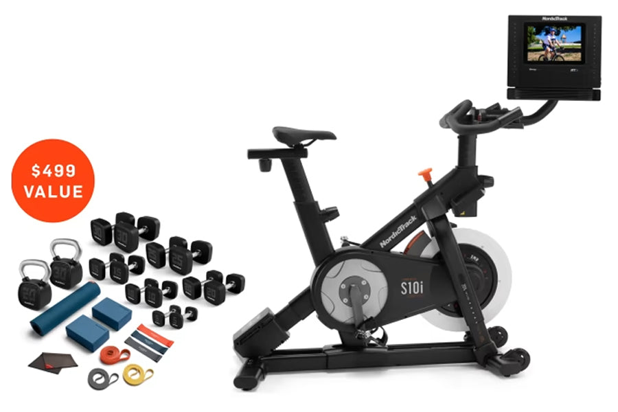 Black NordicTrack S10i indoor exercise bike with tablet display mounted on handlebar, shown with included accessories bundle 