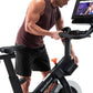 Man in burgundy tank top and black shorts using NordicTrack S15i stationary bike with tablet display showing workout content