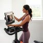 Woman in purple athletic wear using NordicTrack S15i stationary bike with touchscreen display showing workout class