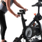 Woman in black leggings and gray tank top using NordicTrack S15i stationary exercise bike with black frame and gray flywheel 