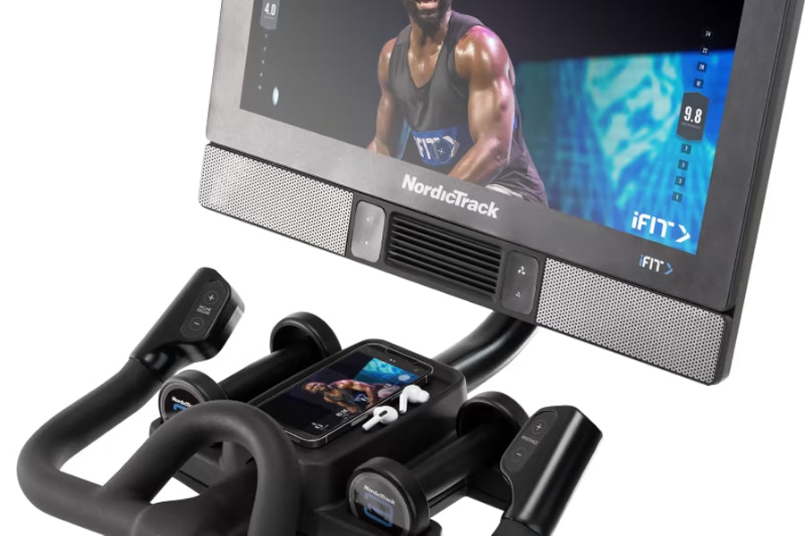 NordicTrack S22i Commercial Studio Bike with touchscreen display showing fitness class, black frame with handlebars and pedal