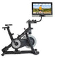 Black and silver NordicTrack S27i stationary exercise bike with attached tablet display showing cycling workout video, on whi