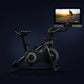 Black NordicTrack S27i stationary bike with integrated touchscreen display showing cycling workout video on dark background