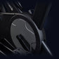 Black stationary exercise bike with ribbed flywheel and digital display on dark background