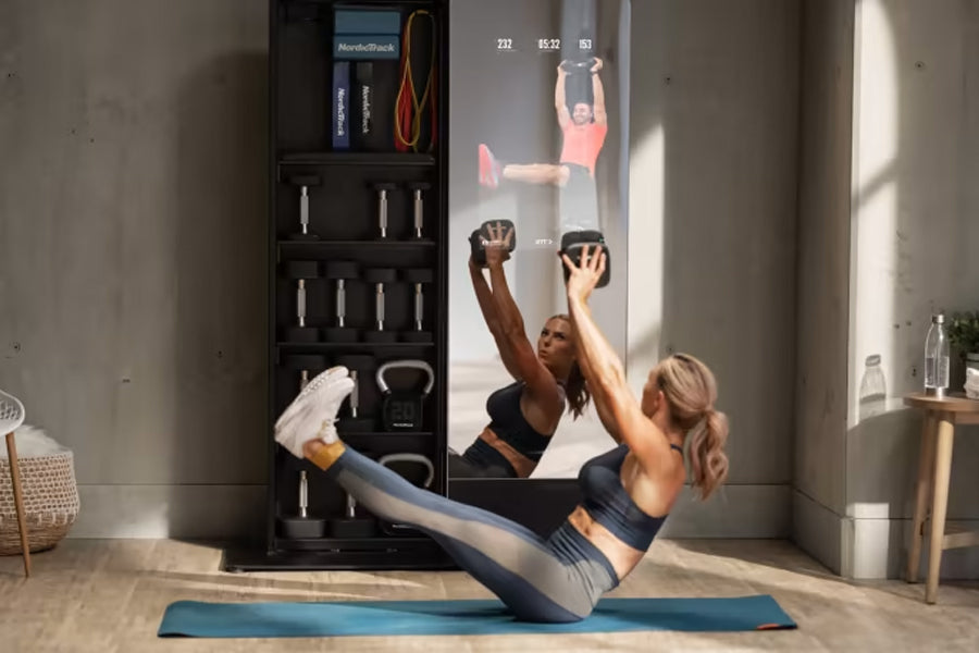 Woman performing core exercise on blue mat in front of NordicTrack Vault interactive mirror with black storage cabinet and fi