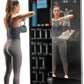Woman performing dumbbell shoulder press exercise in front of NordicTrack Vault interactive home gym mirror with touchscreen 