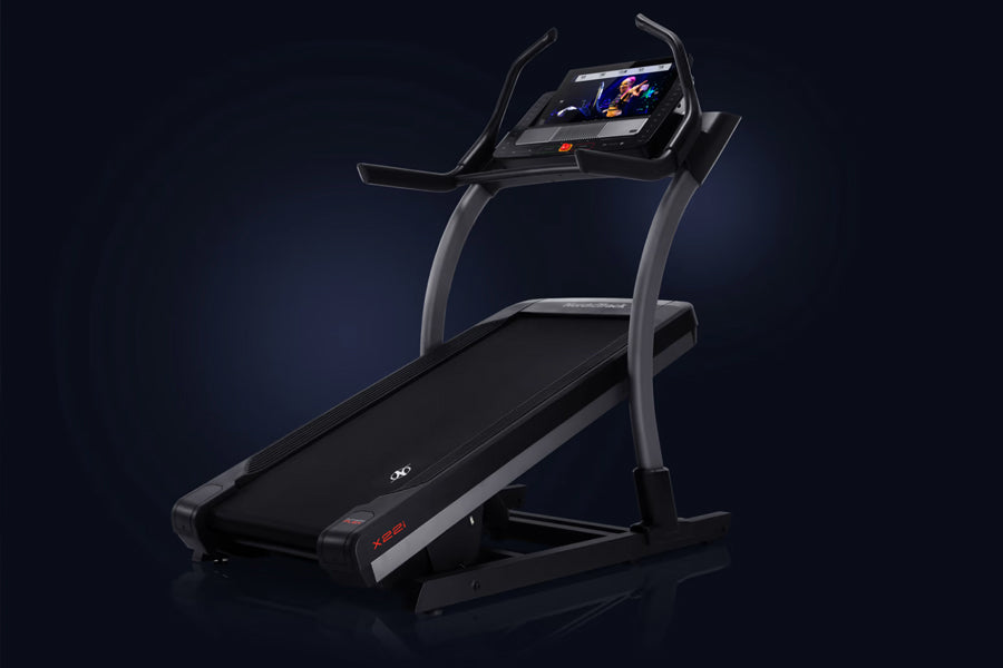 Black NordicTrack X22i commercial treadmill with curved gray frame, digital touchscreen console, and wide running belt on dar