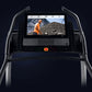 NordicTrack X22i Commercial Treadmill with interactive touchscreen displaying workout video, black frame with dual handles, c