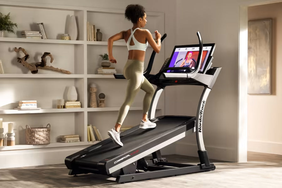 Woman in white sports bra and beige leggings running on black and white NordicTrack X32i treadmill with tablet display in mod