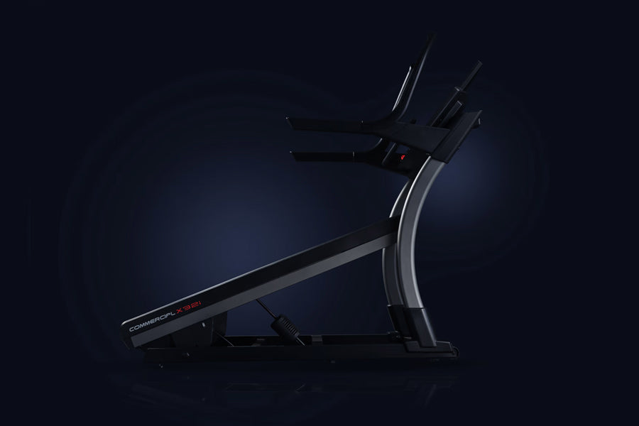 Black and silver commercial treadmill with curved console and digital display on dark background