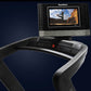 NordicTrack 1750 commercial treadmill with black and silver frame, digital display console showing fitness video, on dark blu