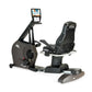 Black recumbent exercise bike with digital display monitor and padded seat, viewed from the side on white background