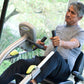 Man in gray shirt using NuStep T4r recumbent elliptical stepper with black seat and silver frame, near window with greenery