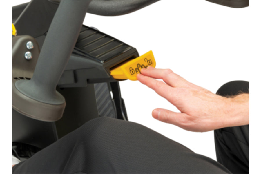 Hand inserting yellow key into NuStep T6PRO recumbent elliptical stepper, showing access panel on black machine