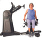 Woman seated on black and gray upper body ergometer machine with dual handles, wearing periwinkle sleeveless top and lavender
