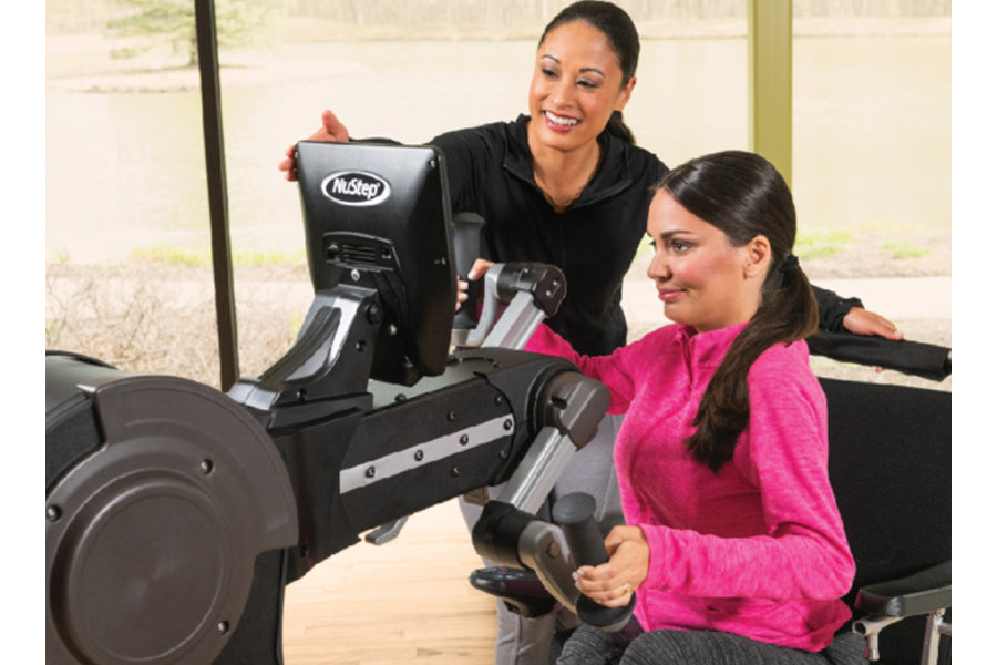 Two women using NuStep UE8PRO upper body ergometer machine with black and gray frame in gym setting